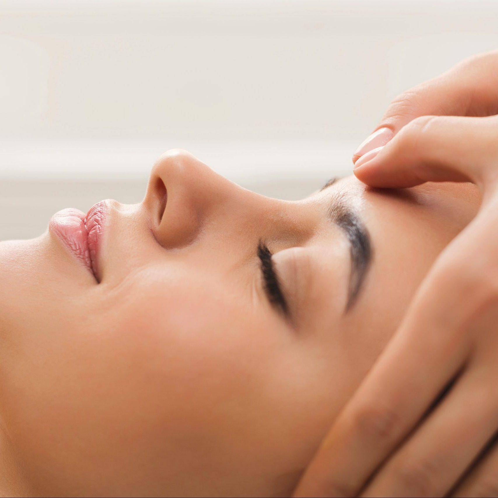 Woman getting professional facial massage at beauty salon